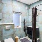 Bathroom with blue tiles, shower, sink, and toilet.