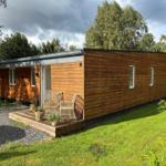 Wooden cabin with terrace and garden. Furniture and plants on the veranda.