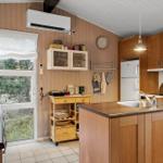 Küche mit Holzschränken, Kücheninsel und Fenster zum Garten.