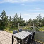 Terrasse mit Tisch und Stühlen, Blick auf Bäume und Himmel.