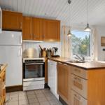 Küche mit Holzschränken, Kühlschrank und Fensterblick