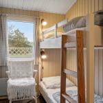 Zimmer mit Doppelstockbett, Stuhl und Fenster mit Blick auf Balkon.