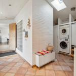 Entrance area with washing machine, fridge, and bench with basket.