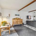 Living room with sofa, sideboard, and TV mounted on the wall.
