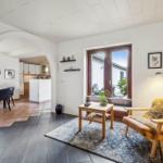 Living area with seating, table, and window to terrace. Kitchen and dining area visible.