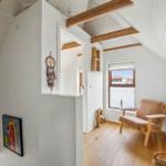 Room with wooden beams, window, chair, and wall decor.