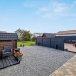 Rear yard with wooden deck, gravel area, and shed under blue sky.