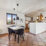 Dining area with table and chairs, kitchen with counter and window.