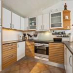 Kitchen with white cabinets, wood fronts, and stainless steel sink.
