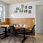 Essbereich mit Tisch, Stühlen und Fensterblick. Wand mit Bildern und Holzverkleidung.