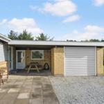 Haus mit Garage, Terrasse und Gartenbereich mit Tisch und Stühlen.
