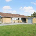 Ein Haus mit Garage und Terrasse im Garten unter blauem Himmel.