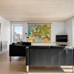 Wohnzimmer mit schwarzen Ledersofas, Holzboden und Europa-Karte an der Wand.