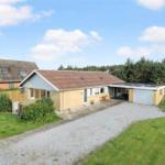 Ein Haus mit Garten, Garage und Terrasse unter blauem Himmel.