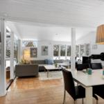 Living and dining area with sofa, table and chairs. Windows show snow.