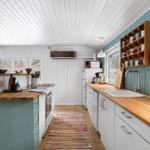 Kitchen with wooden surfaces, blue cabinets, and windows overlooking the garden.