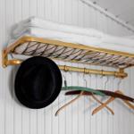 Wall rack with white towels, hat, and coat hangers.