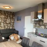 Wohnbereich mit Sofa, Esstisch und Küchenzeile mit Arbeitsplatte und Spüle.