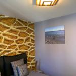 Schlafzimmer mit goldfarbener Wand und Strandbild an der Wand.