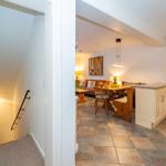 Küche und Essbereich mit Holztisch und -stühlen. Treppenhaus links.