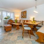 Wohn- und Essbereich mit Holzmöbeln, Fenster und Tür zur Außenseite.