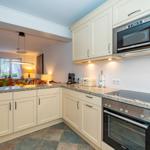 Küche mit weißen Schränken, Steinarbeitsplatte und integriertem Herd und Mikrowelle.