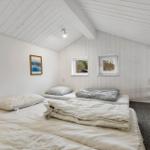 Zimmer mit zwei Betten, weißen Wänden und zwei Fenstern. Decke mit Holzverkleidung.