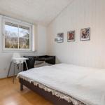 Schlafzimmer mit Bett, Kinderbett und Hochstuhl. Holzwand und Fenster mit Blick.