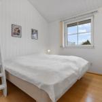 Schlafzimmer mit weißem Bett, Fenster und Holzboden. Links Leiter und Nachttisch.