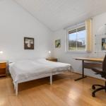 Schlafzimmer mit Bett, Schreibtisch und Fenster mit Blick auf Landschaft.