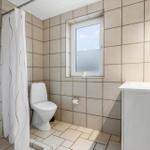 Badezimmer mit Toilette, Waschbecken und Dusche. Fenster mit Blick nach draußen.