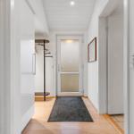Flur mit Holzboden, Teppich und Garderobe. Tür mit Glasfenster und Wandbild.