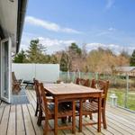 Terrasse mit Holztisch und Stühlen, Blick auf Garten und Wald.