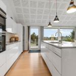 Moderne Küche mit weißer Arbeitsplatte und Blick auf Garten.