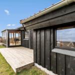 Holzhaus mit Terrasse und Glasveranda. Grünfläche und klarer Himmel.