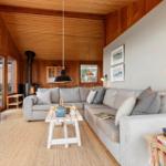 Wohnzimmer mit Sofa, Kamin und Holzwand.