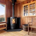 Raum mit Kamin, Holzwand und Fenster zum Blick nach draußen.