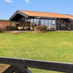 Moderne Villa mit großem Garten und Terrasse. Holzverkleidung und orangefarbener Dachziegel.