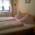 Schlafzimmer mit Holzbett, Fenster und Nachttisch.