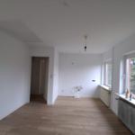 Räume mit Holzboden und Fenstern. Ein Raum mit Durchgang zu einem anderen.