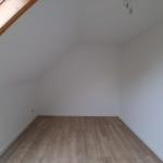 Raum mit Holzfußboden und Dachschrägen, Fenster und Deckenleuchte sichtbar