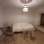 Zimmer mit Bett, Stuhl, Tisch und Decke.