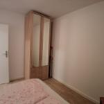 Schlafzimmer mit Bett, Kleiderschrank und Tür.