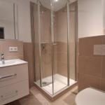 Badezimmer mit Dusche, Waschbecken und Toilette.