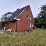 Rotes Backsteinhaus mit Garten, Garage und Satellitenschüssel.