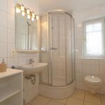 Badezimmer mit Dusche, Waschbecken und Toilette.