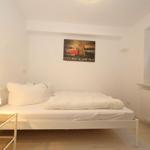 Schlafzimmer mit weißem Bett, Lampe und Wandbild