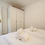 Schlafzimmer mit Bett, Kleiderschrank und Tür