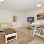 Wohn- und Essbereich mit Sofa, Tisch und Fernseher.