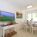 Wohn- und Essbereich mit TV, Tisch und Stühlen, Fenster und Wandbild.